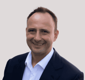 Személyes portré egy magabiztos, mosolygó férfiról, aki a jövő alakítására fókuszál.